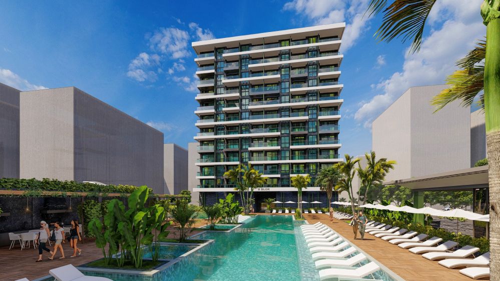 Outdoor swimming pool surrounded by palm trees and tropical landscape.Seafront Luxury Apartments in Mahmutlar – New Investment Project in Alanya