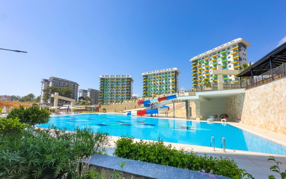 Стильный жилой комплекс с аквапарком и современной архитектурой, идеален для отдыха. Роскошные и комфортные резиденции на побережье Средиземного моря