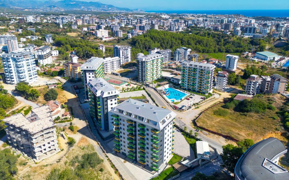 Вид с высоты на современные жилые блоки, расположенные недалеко от моря и окружённые природой. Роскошные и комфортные резиденции на побережье Средиземного моря