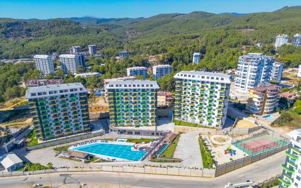 Havuz ve peyzaj alanlarının birlikte görüldüğü, doğa ile iç içe huzurlu bir ortam.Akdeniz Kıyısında Lüks ve Konforlu Rezidans Daireler