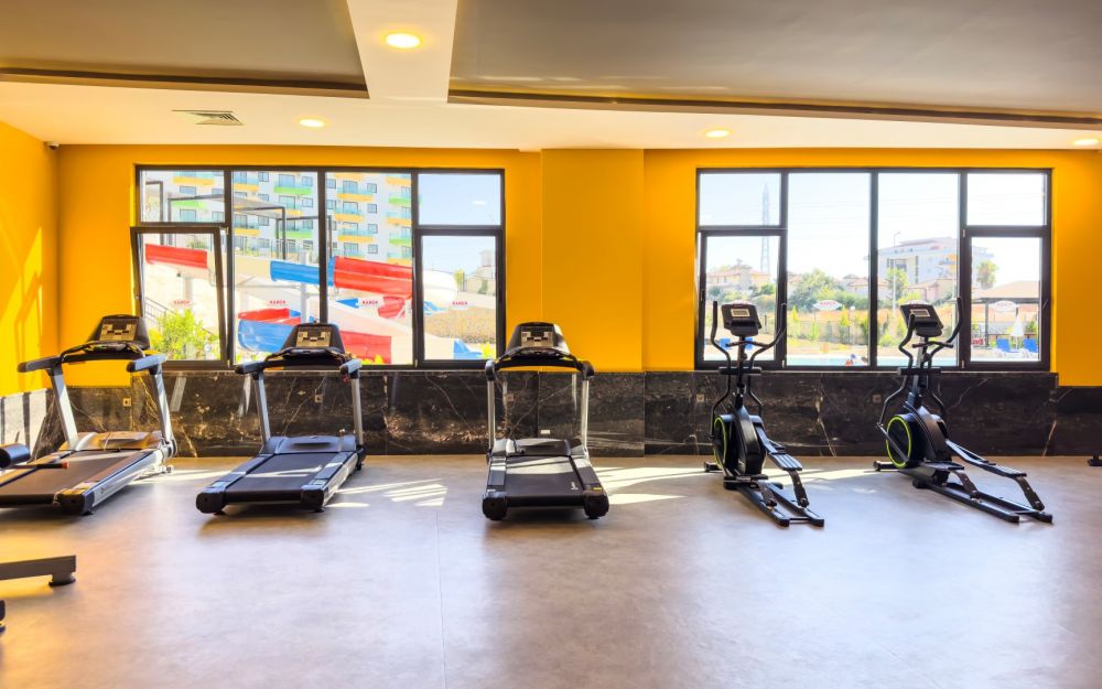 Фитнес-зал с современным оборудованием и панорамными окнами. Роскошные и комфортные резиденции на побережье Средиземного моря