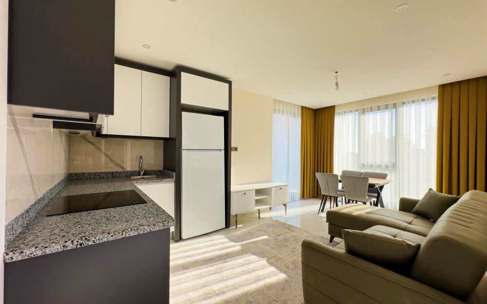 Кухня и гостиная открытого плана с встроенной техникой и обеденной зоной. Роскошные и комфортные резиденции на побережье Средиземного моря