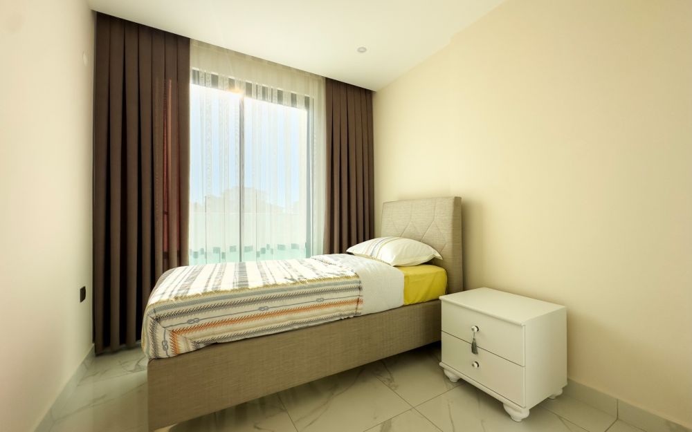 Уютная спальня с большими окнами и элегантными декоративными элементами. Роскошные и комфортные резиденции на побережье Средиземного моря