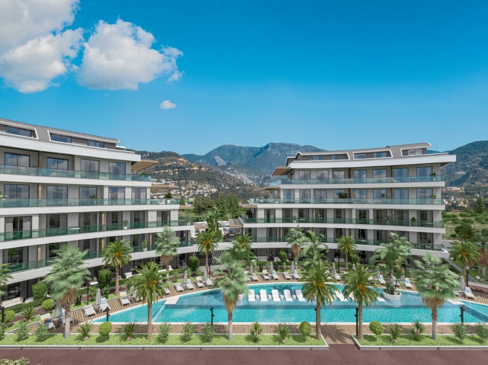 Oba’daki modern lüks projenin geniş havuz alanı ve panoramik dağ manzarası.Alanya Oba’da Ultra Lüks Konut Projesi